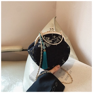 Close-up of floral embroidery on navy blue shell bag with gold chain strap