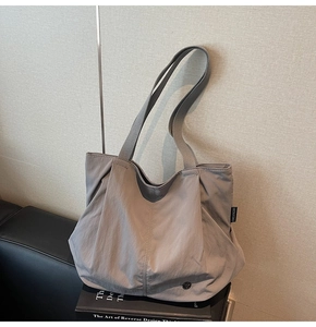 Close-up of gray nylon tote bag featuring vertical stitching and metal button detail