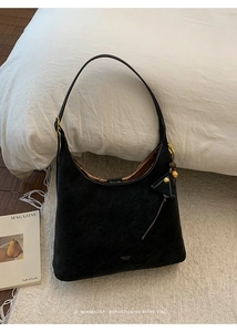 Detail of black matte hobo bag featuring golden hardware and leather triangle charm