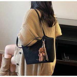 Détail d'un grand sac cabas noir avec coutures blanches et un pendentif ours mignon