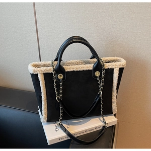 Detail of black suede tote bag with white lamb wool trim and metal chain shoulder strap