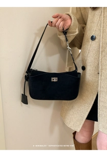 Close-up of minimalist black suede shoulder bag with silver square twist lock detail