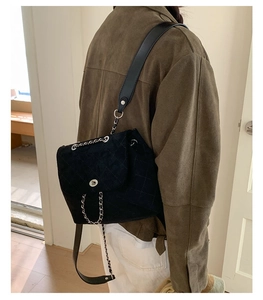 Detail of black quilted velvet backpack with silver chain strap and metal turn-lock