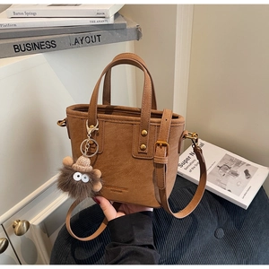 Caramel frosted leather bucket bag with adjustable strap and cute plush monster charm detail