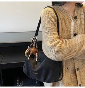 Détail du sac à bandoulière en cuir noir avec breloque étoile et accessoires chaîne