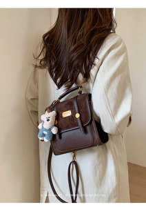Detail of vintage dark brown backpack with contrast panels and a cute bear charm