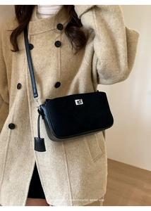 Detail of vintage black crossbody bag featuring silver hardware on tweed coat
