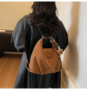 Détail du sac demi-lune en cuir marron foncé avec logo doré et pendentif d'ours