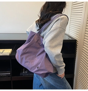 Detail showing the purple large tote bag texture and wide strap on a model's shoulder