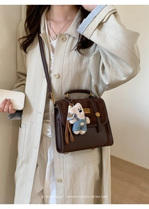 Detail of vintage brown leather backpack with bear charm on a female model in a trench coat