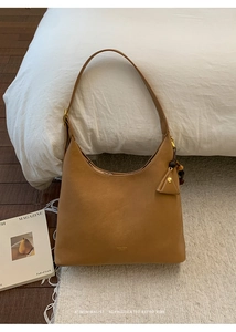 Detail view of caramel matte leather hobo bag with gold logo and triangle tag decoration