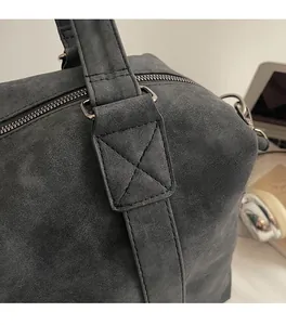 Detail view of reinforced stitching and silver hardware on a large grey suede tote bag