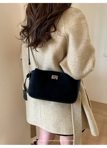 Chic retro black suede crossbody bag with silver rotating clasp worn over a beige coat
