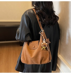 Détail du sac à bandoulière en cuir marron avec breloque ours et pendentif étoile