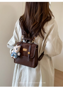 Detail of retro dark brown backpack with suede texture and cute teddy bear charm