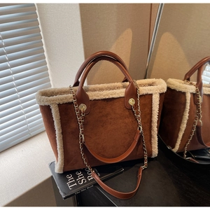Detail of brown suede tote bag with white faux fur trim and gold chain strap accent