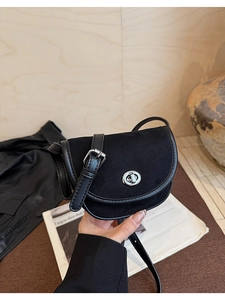 Detail of matte black saddle bag with silver twist lock and adjustable leather strap