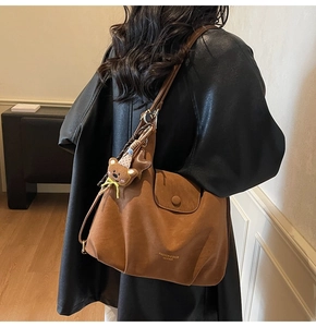 Détail du sac à main marron avec logo doré et charmant pendentif d'ours en peluche