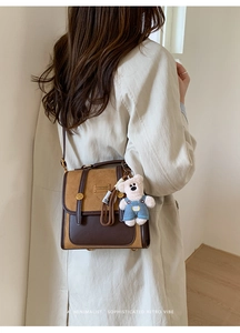 Close-up of retro color-block backpack with metal logo and cute white bear charm detail
