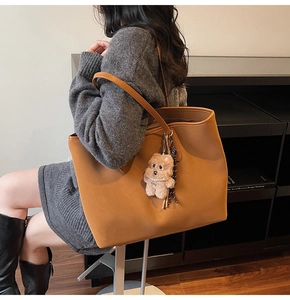 Braune Leder-Einkaufstasche getragen von Model im minimalistischen Interieur mit Plüsch-Anhänger
