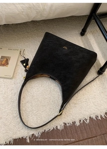 Detail of black matte suede tote with leather tassels and vintage beaded charm