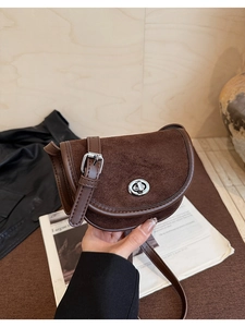 Detail of dark brown saddle bag with matte finish and silver twist-lock closure