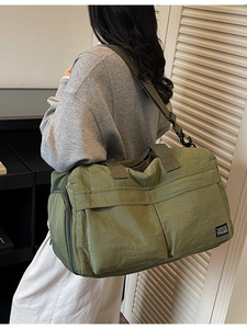 Olive green large capacity travel duffel bag with shoulder strap worn by a model