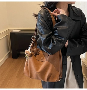 Détail du cabas vintage en cuir marron avec logo mode et pendentif ours mignon