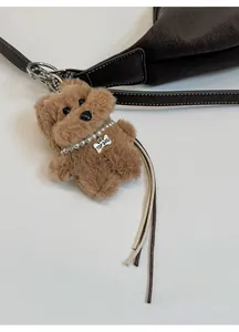 Brown faux fur dog charm with pearl necklace and bone tag on a leather bucket bag