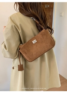 Close-up of retro brown suede underarm bag with silver hardware and leather charm detail
