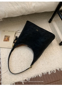 Detail of black matte suede tote bag featuring white contrast stitching and gold buckle