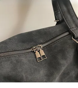 Detail of premium smooth dual metal zippers on high-quality charcoal gray suede tote bag