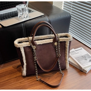 Detail of brown suede tote bag featuring plush white faux fur trim and gold chain straps
