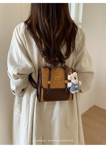 Detail of vintage patchwork leather backpack on beige coat with cute plush bear charm