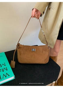 Close-up of brown suede underarm bag with silver buckle and matching handle detail