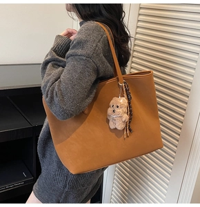 Detail einer großen braunen Leder-Shopper-Tasche mit süßem Bärenanhänger am Schultergurt