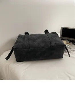 Detail of large black tote bag showing reinforced stitching and matte textured material