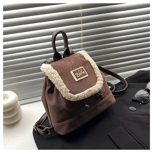 Macro detail of brown suede backpack featuring plush sherpa trim and bear patch embroidery