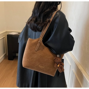 Grand sac cabas marron en daim avec bretelles et charm ourson sur l'épaule du mannequin