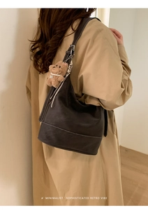 Detail of dark brown retro bucket bag with contrast stitching and cute plush bear charm