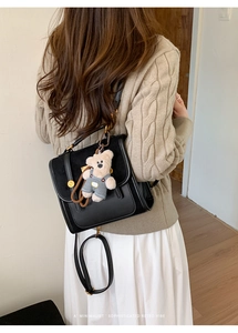 Detailed view of the black retro leather backpack with a cute plush bear pendant accessory