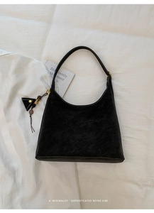 Detail view of black hobo bag with white contrast stitching and triangle pendant detail