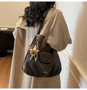 Détail du sac à main en cuir marron foncé avec breloques sur trench-coat kaki