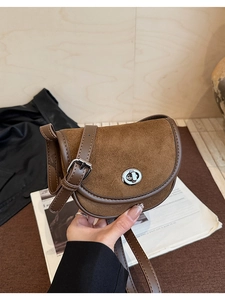 Detail of vintage brown suede saddle bag featuring silver metal twist lock and slim strap