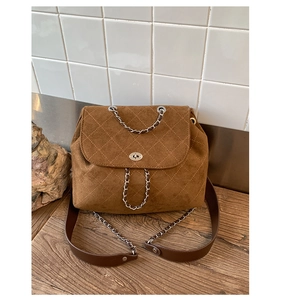Detail of dark brown quilted suede backpack with silver twist lock and metal chain