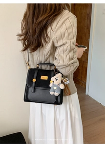 Detail of vintage black patchwork leather backpack with cute teddy bear charm on model