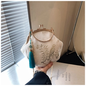 Detailed close-up of bird and floral embroidery on a retro shell bag with chain strap