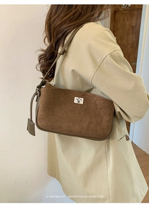 Close-up of retro brown suede shoulder bag with silver turn-lock and smooth leather trim