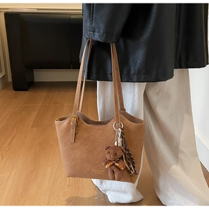Gros plan d'un cabas en cuir vintage marron avec breloque ours et détails du logo MKAKCI