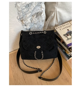 Close-up of black quilted bucket bag with silver metal chain strap and twist-lock